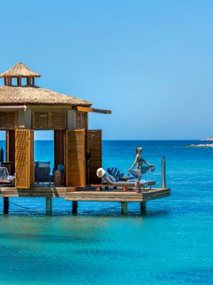 A guest relaxing on a private cabana above turquoise waters at Rixos Premium Belek, Infinia Vacation Club.